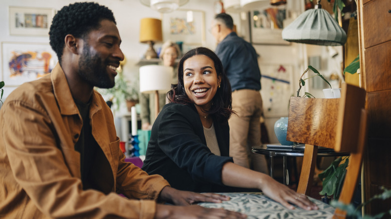 Two people talking by a chair at an estate sale