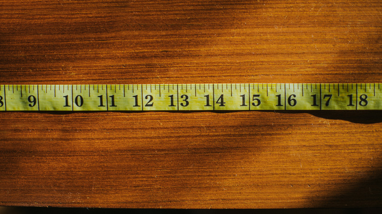 A person measuring a wooden table with a tape measure