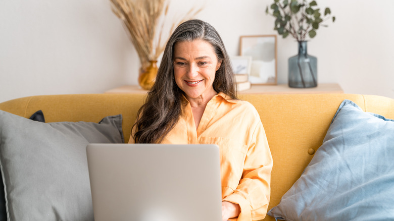 A woman sitting on the couch looking at her computer
