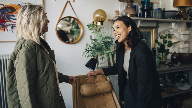 Two people talking near a chair in a home