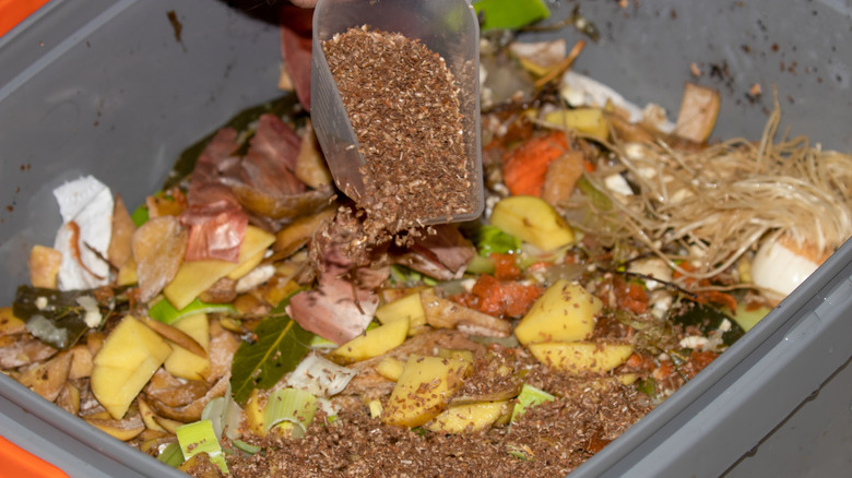 Person mixing Bokashi bran with waste to create compost