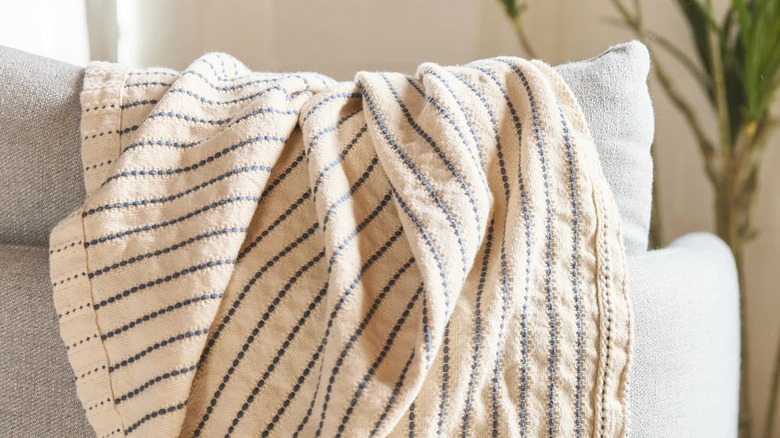 An organic beige cotton throw blanket with gray stripes on a couch