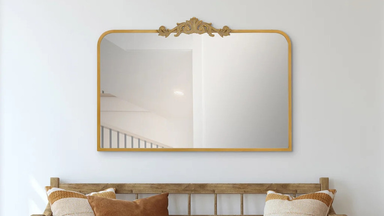 An antique style large gold mirror on a white wall
