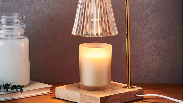 A fluted gold candle warmer lamp with a wood base