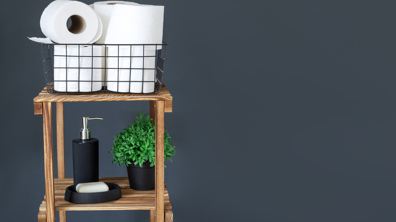 Toilet paper rolls in basket on plant stand