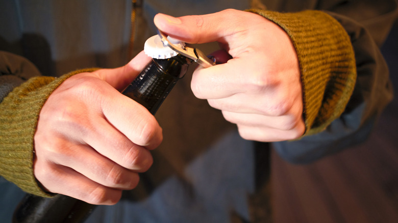 Hangs using bottle opener to open glass bottle