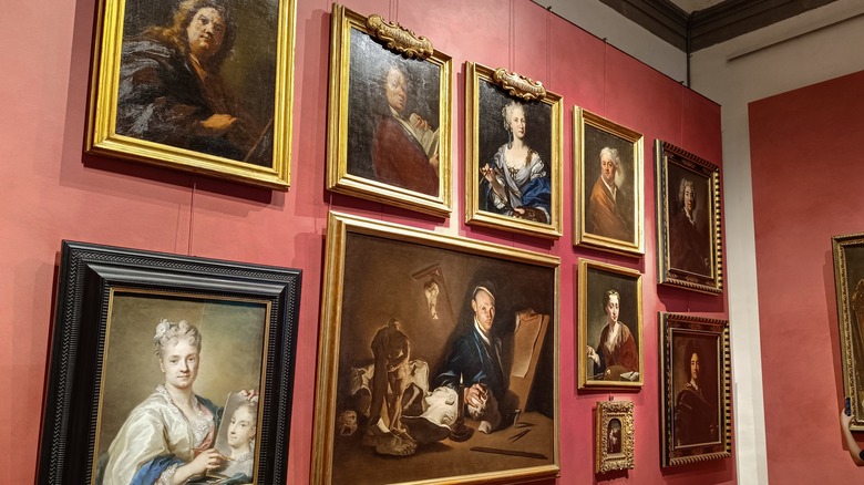 painted portraits hanging on a pink wall