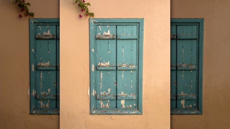A rustic, sea green window frame and wood blinds