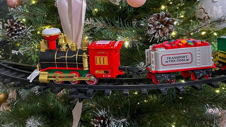 Closeup of a Santa-themed model train going around a tree