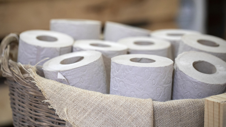 Toilet rolls neatly contained in a basket lined with beige fabric