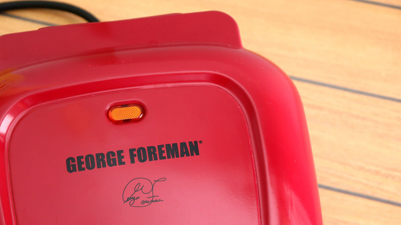 A red George Foreman grill on a wooden countertop.