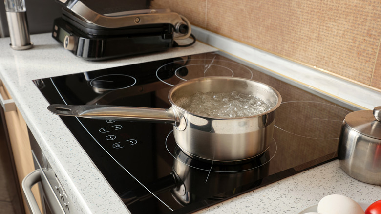 Water boiling in a silver saucepan on an induction cooktop.