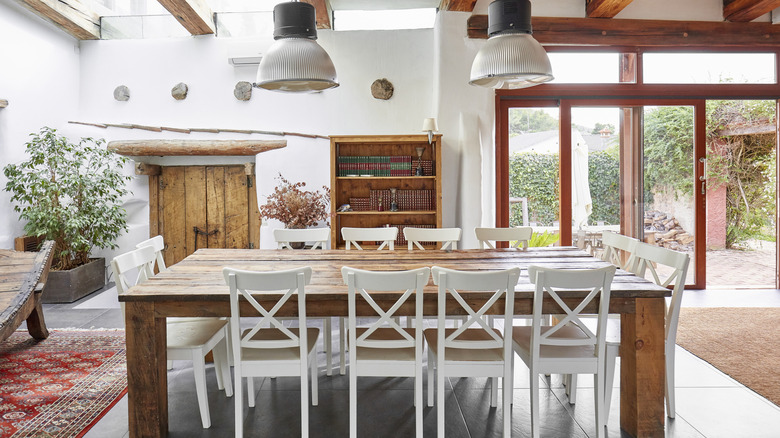 Mediterranean kitchen and dining area with a large wood table, white chairs, and natural light.