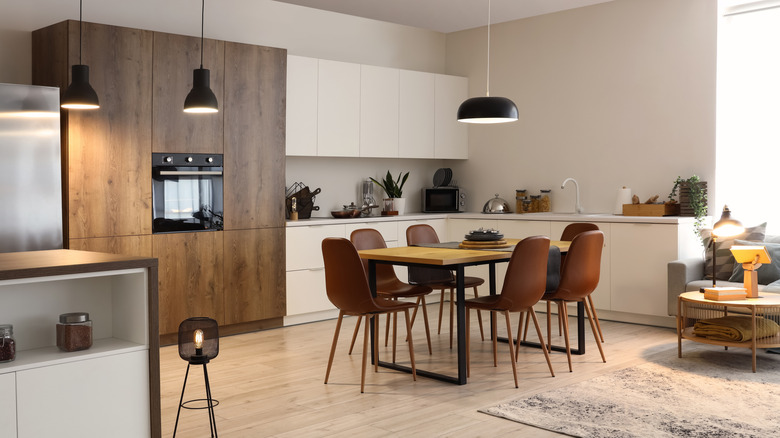 Modern dining room with wood cabinets, wood table and brown chairs, and pendant lighting.