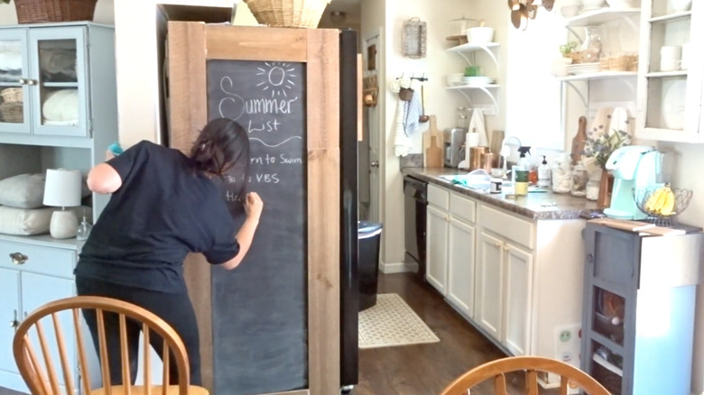 Woman draws on DIY chalkboard fridge