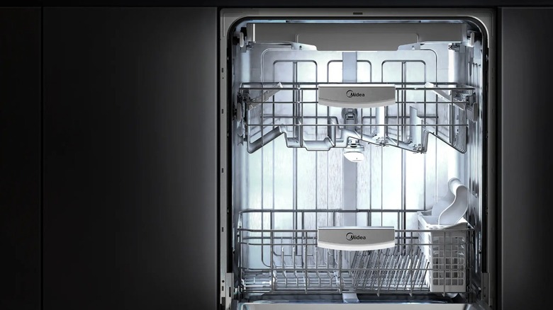 The lit up interior of a Midea dishwasher in a dark kitchen