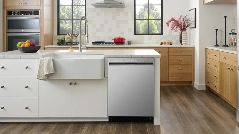 A silver dishwasher installed near a white sink on one end of a kitchen island
