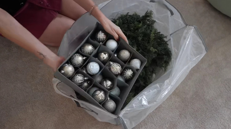 A person storing holiday decorations in a clear storage bag.