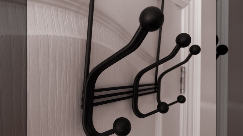 A black multi-coat hanger rack on the back of a white door.