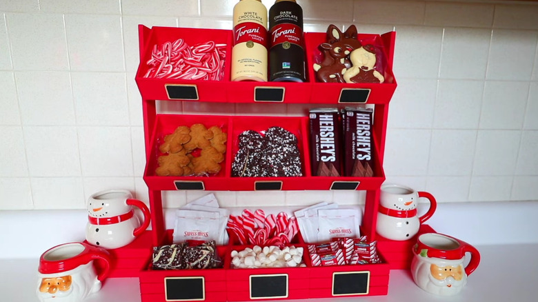 A DIY hot chocolate bar with ingredients in it and mugs on the sides.