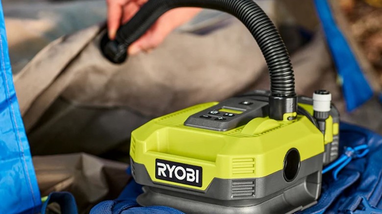 A Ryobi Inflator Tool inflates a gray air mattress.