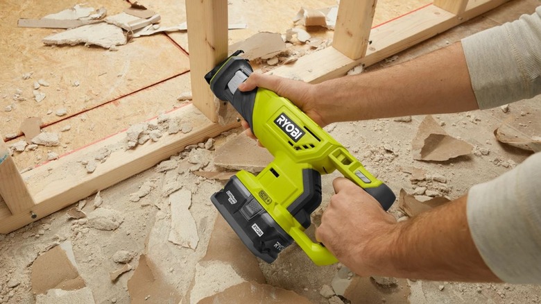 A contractor cuts through wood studs with the Ryobi Reciprocating Saw.