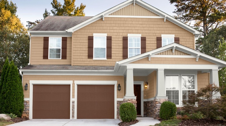 Beige home with brown garage doors and shutters