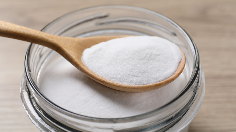 Baking soda being scooped in a glass jar