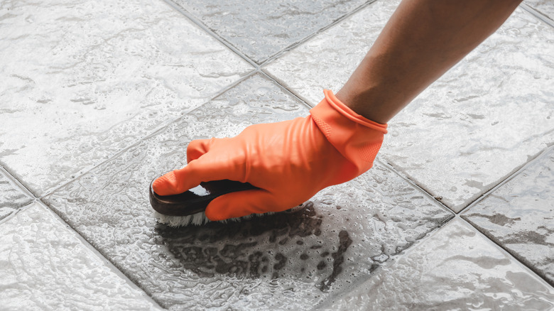 Closeup of person wearing gloves scrubbing kitchen floor