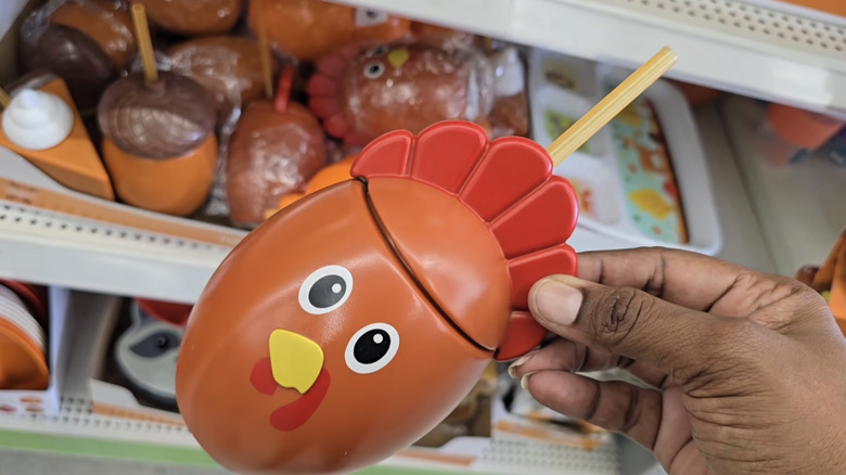 A person holding a cup that looks like a turkey in a Dollar Tree store