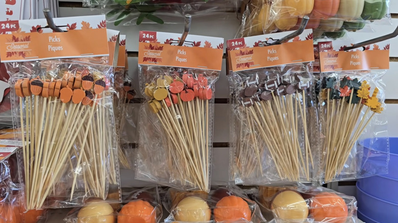 Four 24-packs of wooden picks shaped like acorns, pumpkins, footballs, and leaves hanging in a Dollar Tree
