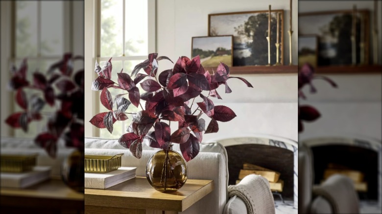 An arrangement of black plum leaf sits on a sofa table