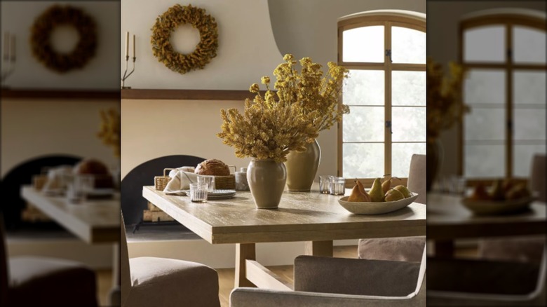 Golden wheat fills two cream vases in a fall tablescape