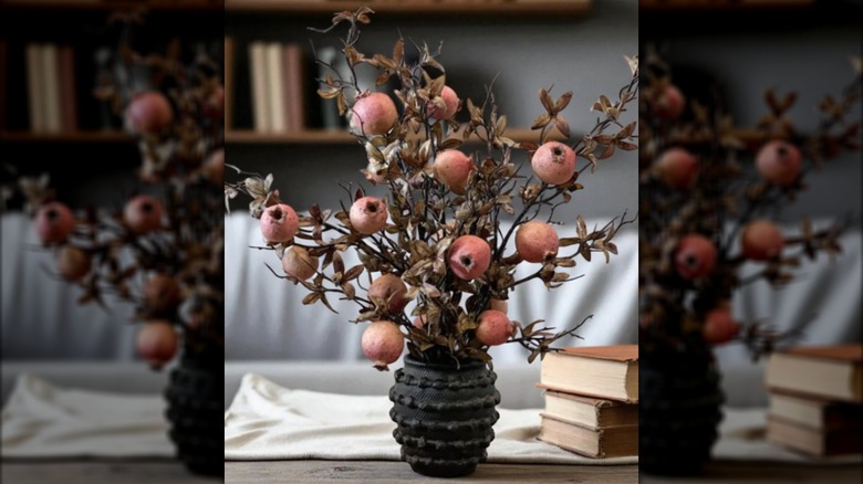 Faux pomegranate branches in a black vase
