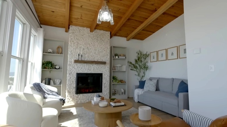 A beautiful living room in a coastal interior design style with a fireplace and a bookcase concealing the entry to a powder room.