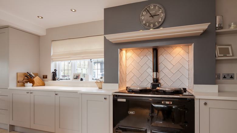 Pretty range alcove with a stone backsplash, lighting, and gray paint