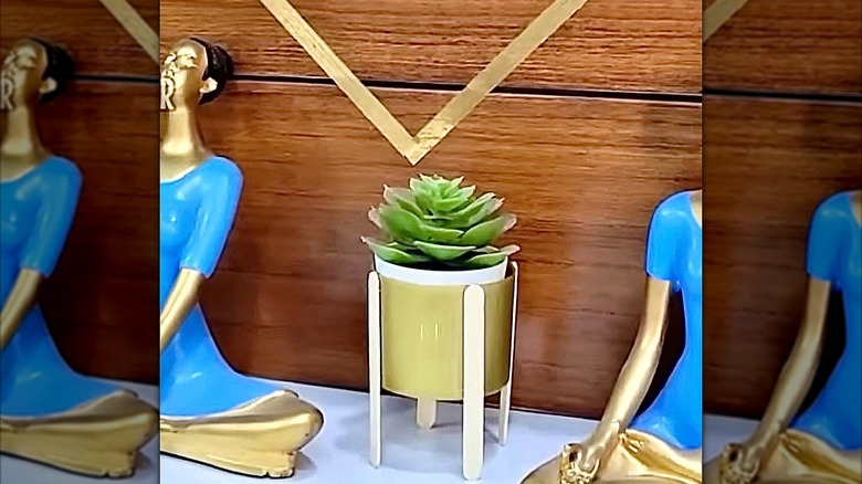 A mini plant growing in a stand made from a laundry detergent cap.
