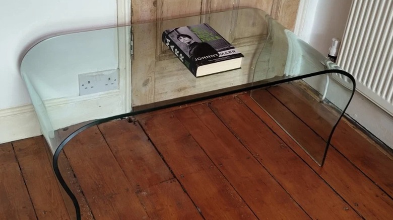 curved glass coffee table with a book on it