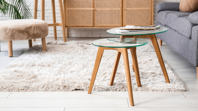 two small round glass coffee tables on a white carpet by a couch