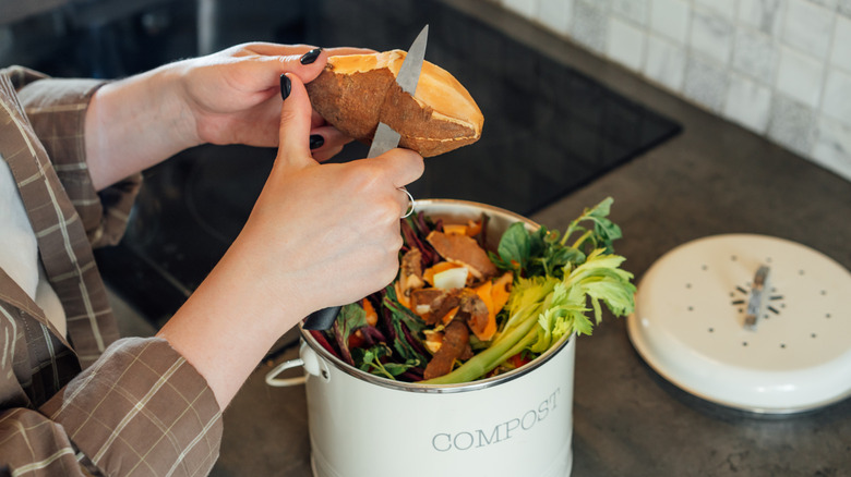 Woman composting fruit and vegetable scraps in the kitchen at home