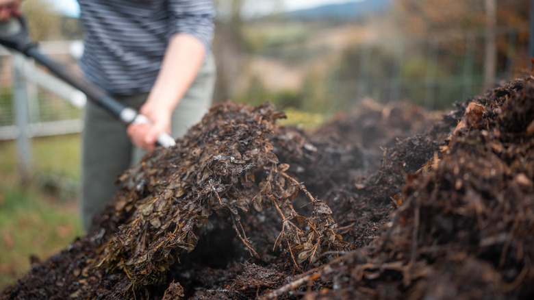 Person turning a pile of compost