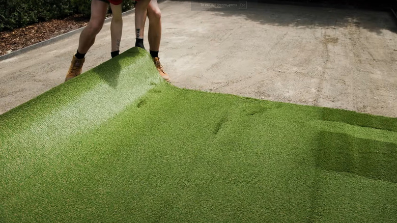Person laying artificial turf in small prepped area