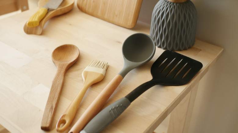 Spoons, spatula and culinary brush on wooden table.
