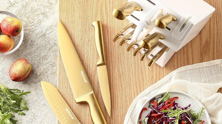 Gold knives on top of a wooden cutting board