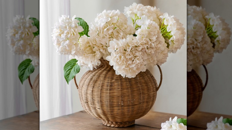 Large rattan vase with artificial white hydrangeas inside