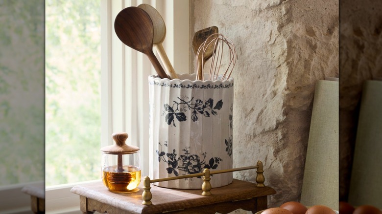Floral-patterned utensil crock holding kitchen utensils inside