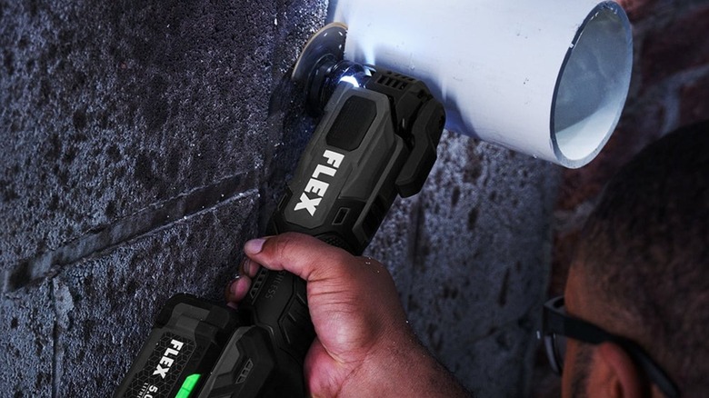 Man using Flex 24V Oscillating Multi-Tool Kit to cut PVC pipe