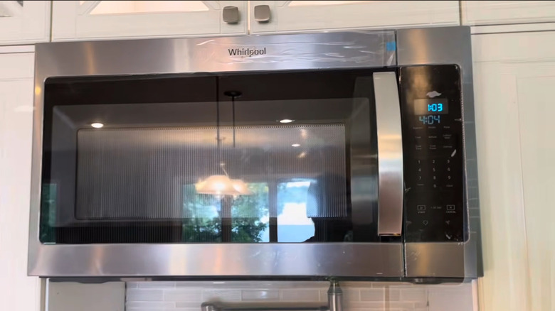 Whirlpool's 1.7 cubic feet Over-the-Range Microwave installed under cream colored cabinets