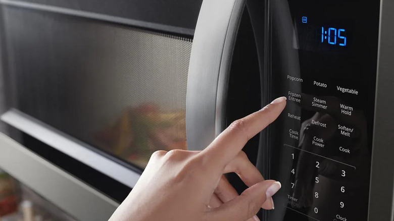 Hand pressing control pad on Whirlpool's 1.9 cubic-feet Over-the-Range Microwave