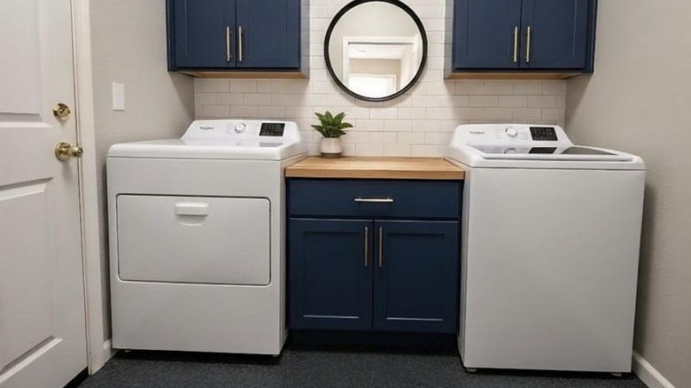 Whirlpool's 7-cubic-feet Vented Electric Dryer with a Whirlpool washer, both housed in an attractive utility space with blue cabinets